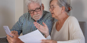 A senior man and woman discussing papers they are reading